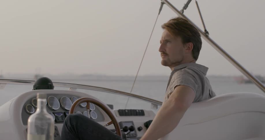 A man sits by the wheel of a boat