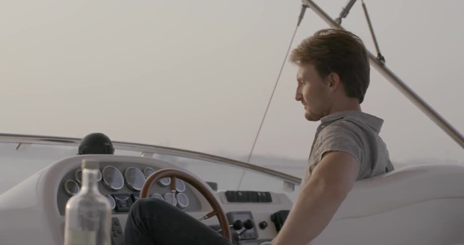 A man is sitting at the wheel of a boat