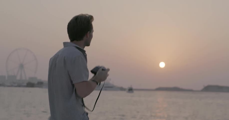 Man takes pictures of a body of water at sunset