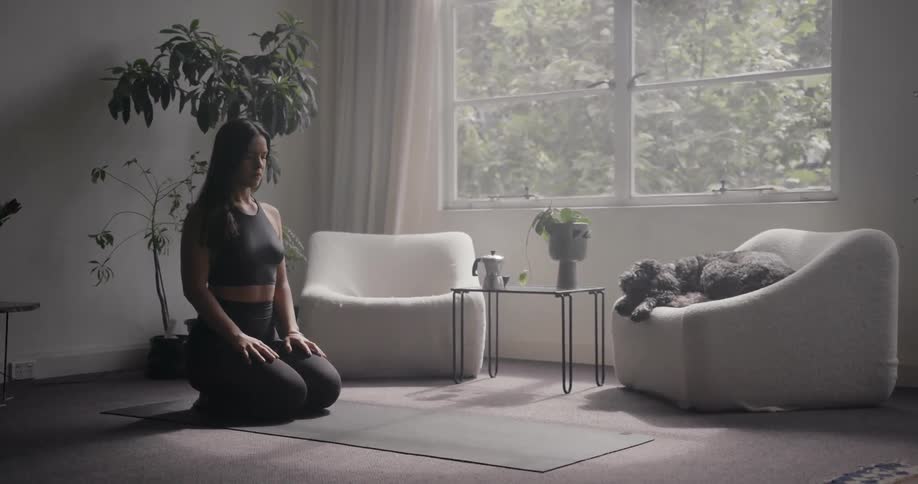 A woman is kneeling in her living room