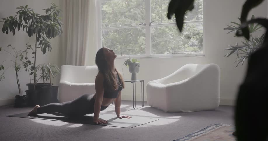 Woman practices yoga in the living room on a sunny day