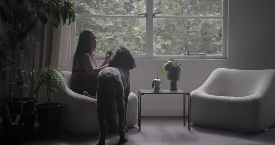 A woman pets a dog while sitting in a chair