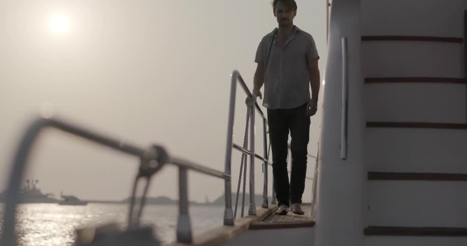 A man walks around the side of a boat in the water