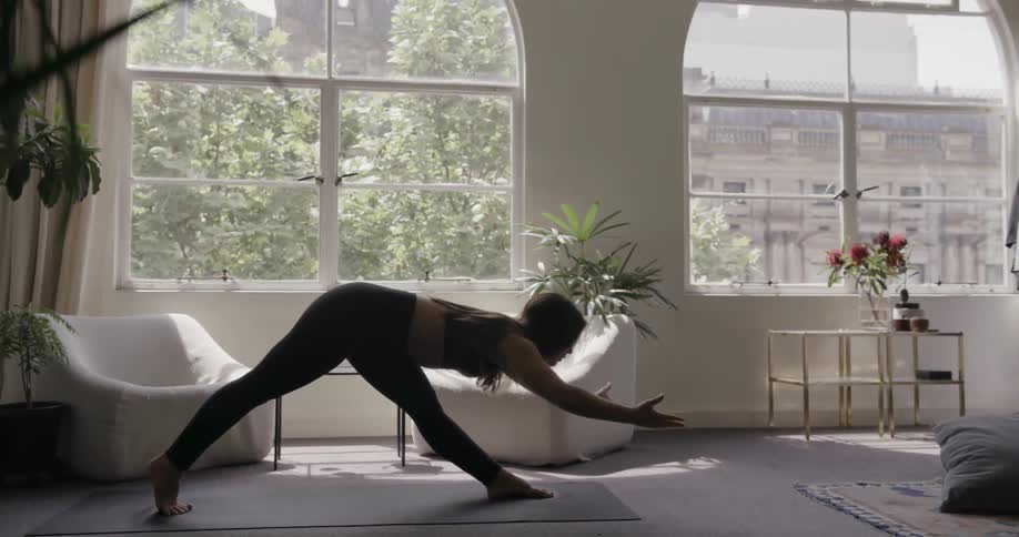 A woman does yoga on a mat in the living room
