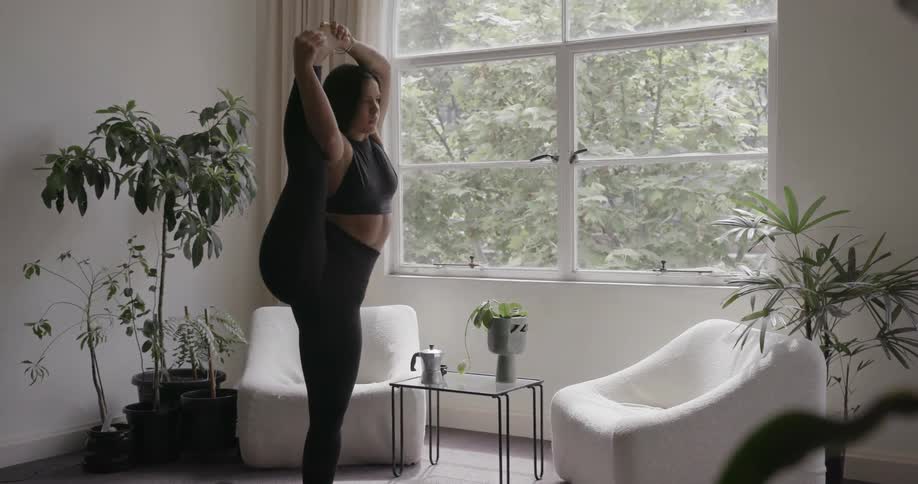 A woman is performing yoga in her home