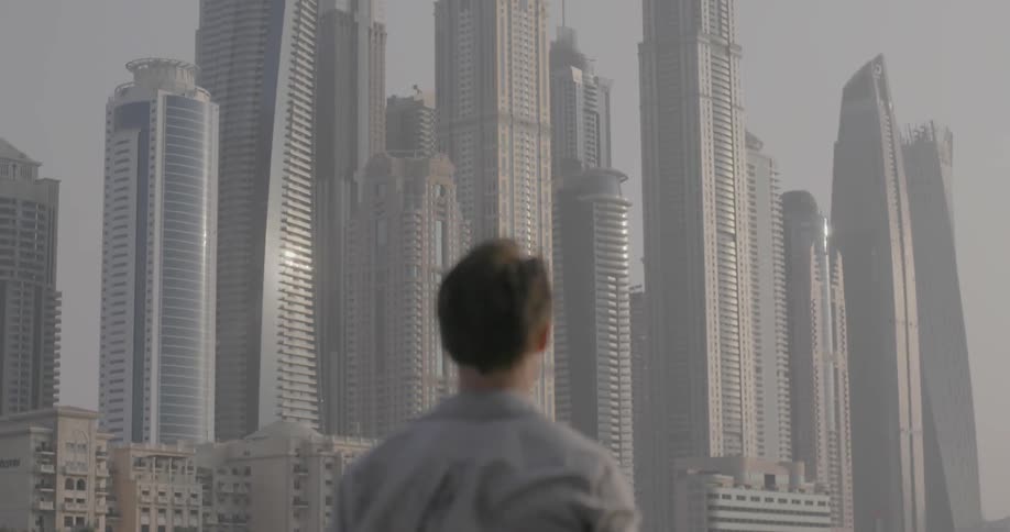 Man takes pictures of a city skyline on a windy day
