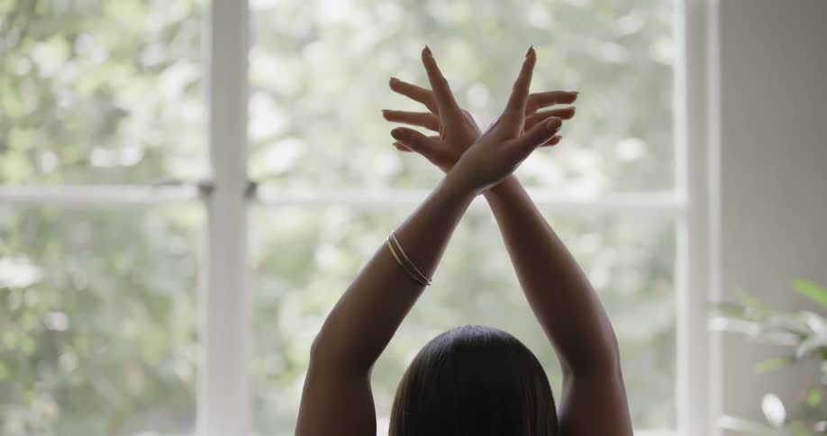 Woman sits with arms crossed above her head