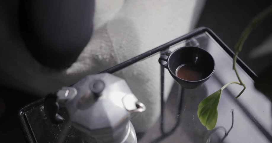 A woman places a teacup on a glass table