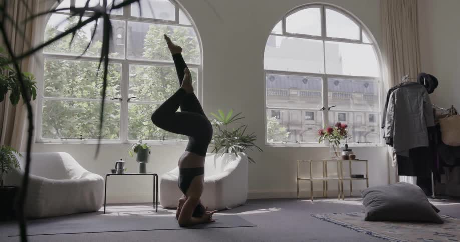 A woman is standing on her head kicking her legs up