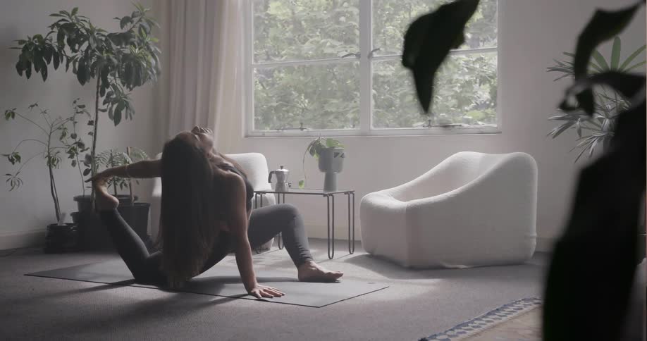 Woman practices yoga in the living room on a sunny day
