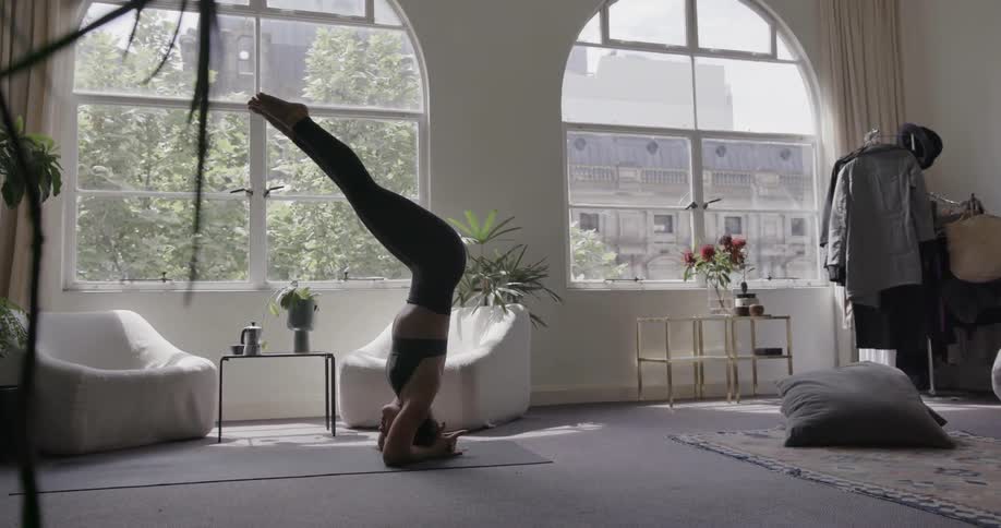 Woman practices yoga in the living room on a sunny day