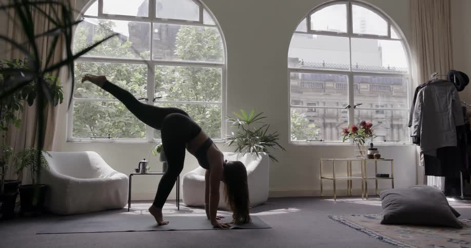 Woman stretching acrobatically in a large apartment