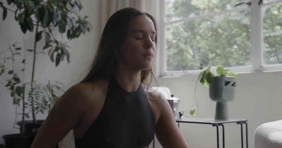 Woman doing yoga stretches on mat in living room during the day