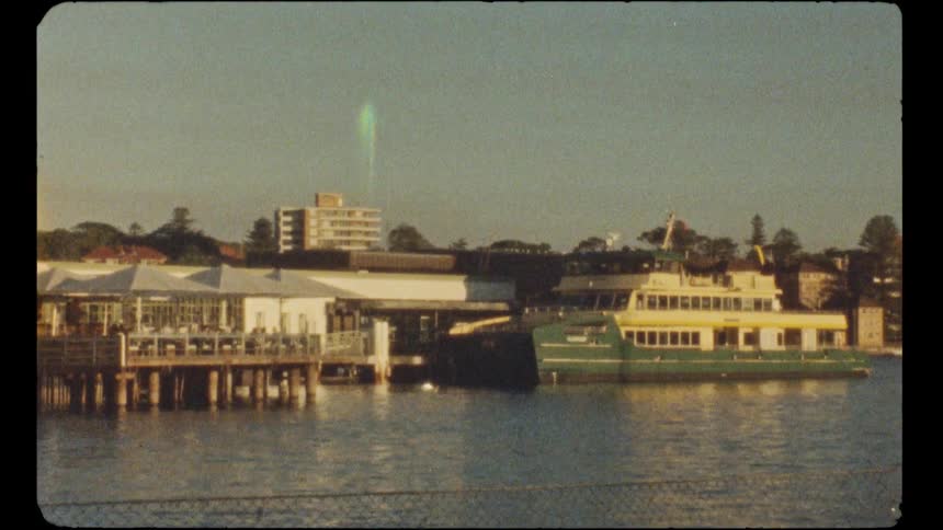 A classic green and yellow Sydney ferry is docked at a waterfront pier in this archival film clip