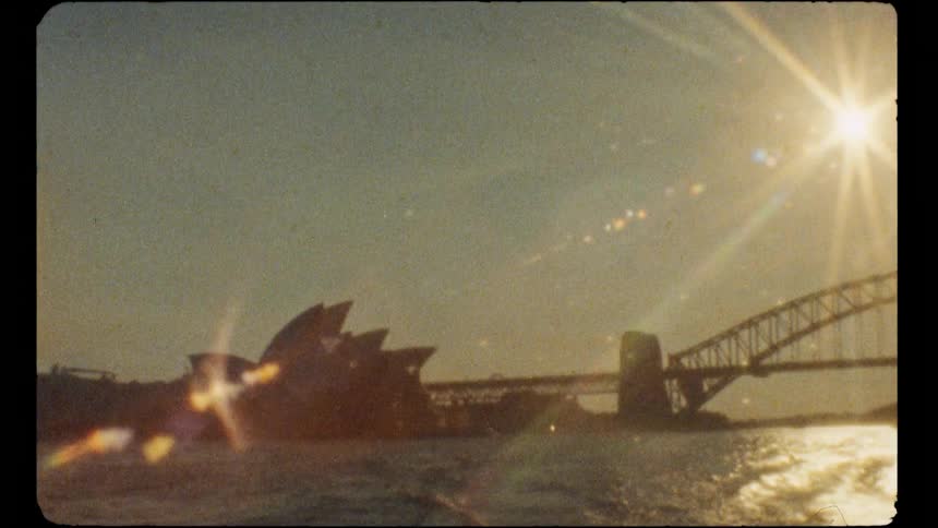 Super 8mm style footage shows the Sydney Opera House and Harbour Bridge silhouetted against a bright, setting sun