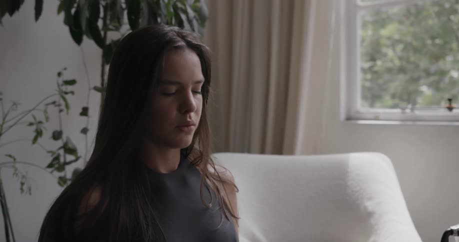 A young woman is deep breathing as she meditates