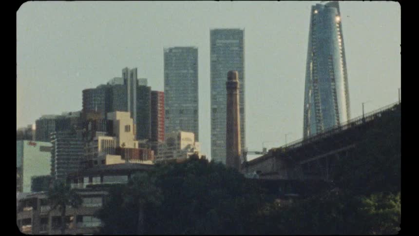Vintage Super 8 film captures a view of the modern Sydney city skyline with skyscrapers and a bridge