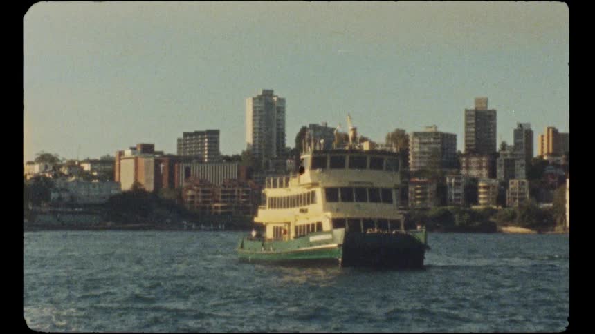 Archival film captures a ferry sailing across the harbour with the Sydney cityscape visible on a sunny day