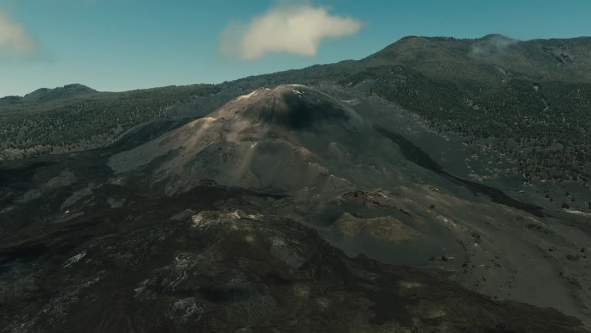 Epic aerial footage reveals a dormant volcano with steam gently rising from its crater amidst a barren, rocky landscape