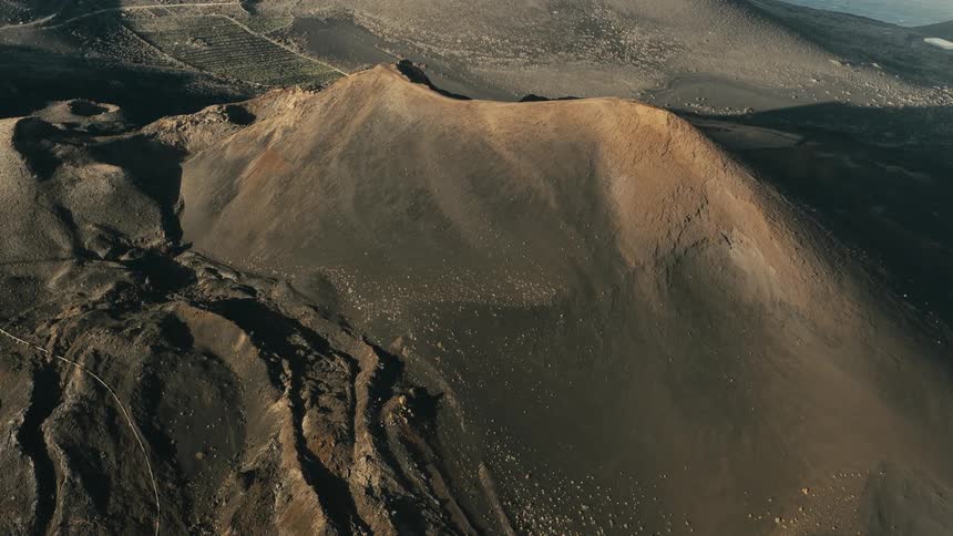Static aerial time-lapse capturing the movement of sunlight and shadows over a vast volcanic crater