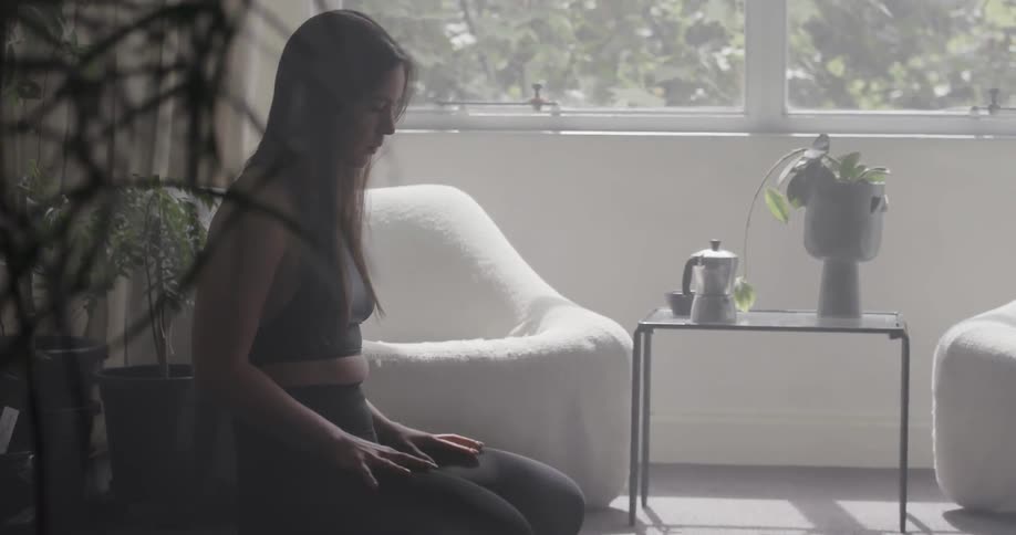 Woman practices yoga in the living room on a sunny day