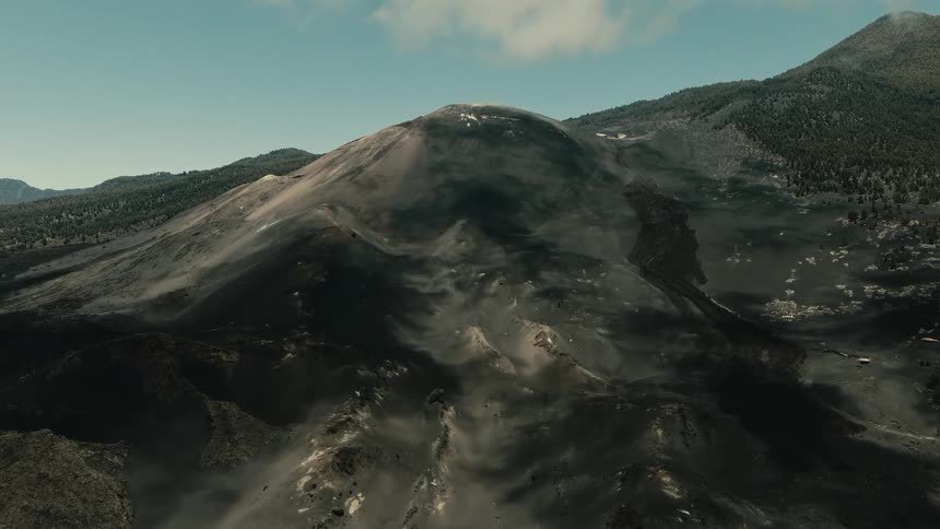 Epic aerial view slowly retreats from a smoking volcanic crater, showcasing the vast and otherworldly landscape of dark ash and lava fields