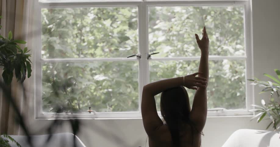 A woman raises her arms doing yoga at home