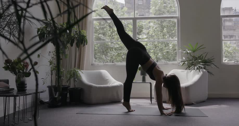 A woman raises her leg high and stands on her head