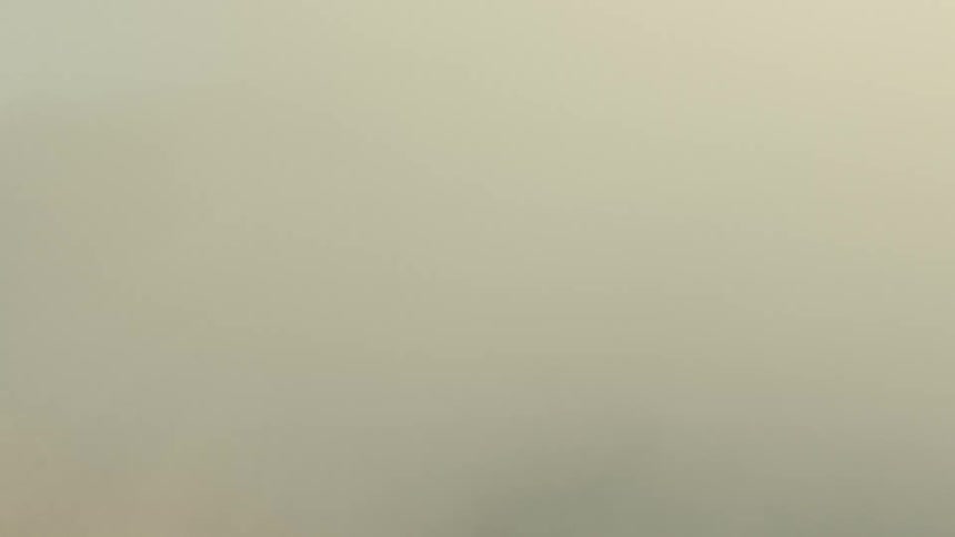 An aerial shot flies backwards through thick clouds to reveal the dark, ashen crater of a dormant volcano