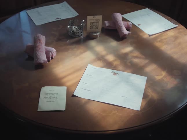 A restaurant table is set with menus, rolled towels, a handwritten note, and a QR code for contactless ordering