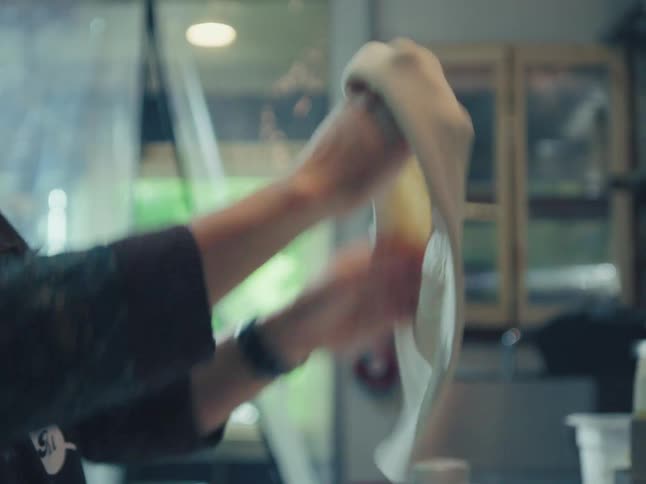 Close up of a professional chef expertly kneading and stretching fresh pizza dough in a commercial kitchen