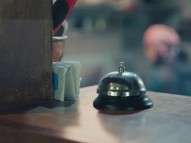 A silver service bell sits untouched on a wooden front desk in a quiet establishment