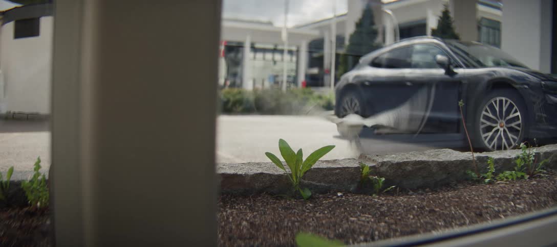 A seagull perches on a curb in a modern parking lot before taking flight in slow motion