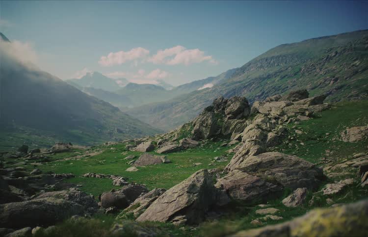 A breathtaking static view of a lush green and rocky mountain valley on a beautiful sunny day