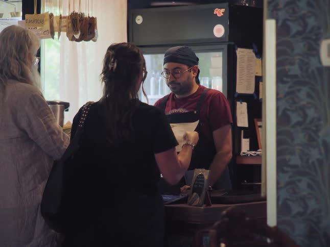 A friendly cashier talks with customers as they place their order at a cozy local cafe