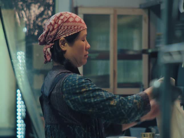 A female chef prepares a pizza from scratch, skillfully stretching the dough and spreading on the tomato sauce