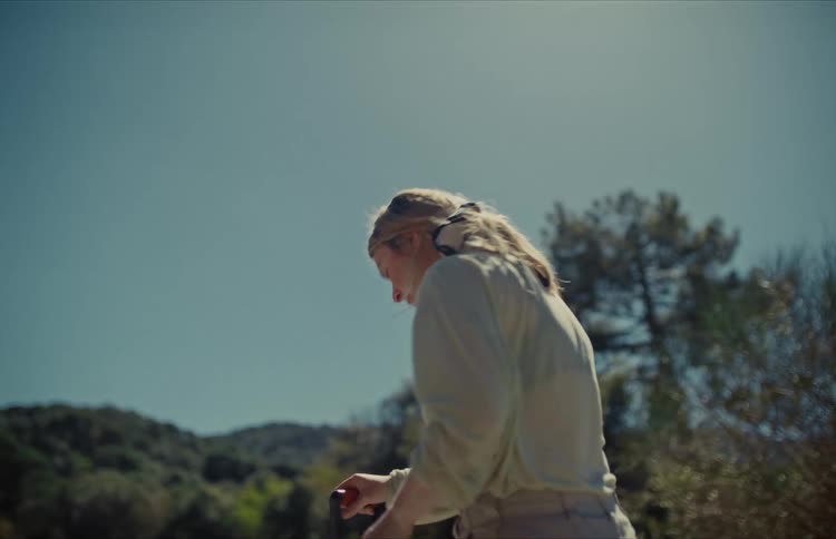A woman works hard, digging with a shovel in a sunlit field in slow motion