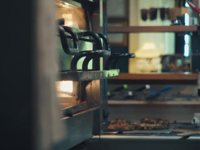A female chef in a professional kitchen takes a hot pizza out of the oven with a peel