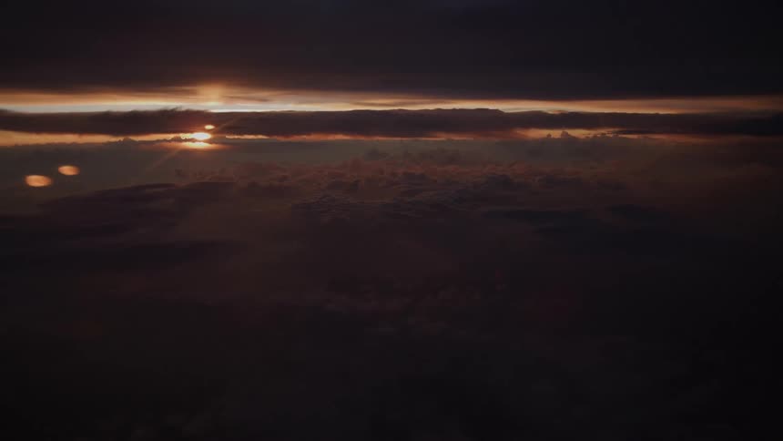 A breathtaking aerial view captures the last rays of sunlight over a dark and moody cloudscape at sunset