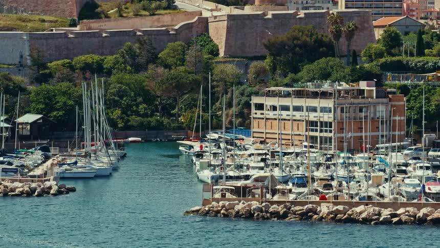 A beautiful sunny day at a scenic marina filled with yachts and boats docked below a historic stone fortress