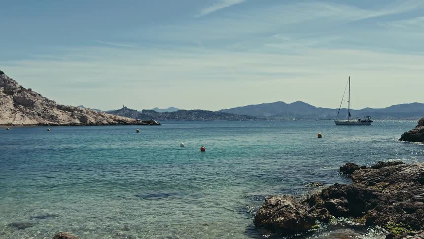 A tranquil bay with crystal clear water and a sailboat anchored off the rocky coast of Marseille, France