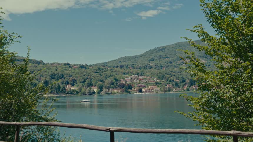 A tranquil view of a picturesque lakeside town nestled on a verdant hillside on a sunny day