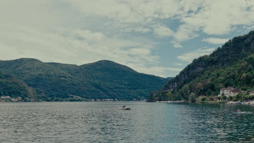 A tranquil wide shot of a scenic mountain lake with a small boat floating on the calm water