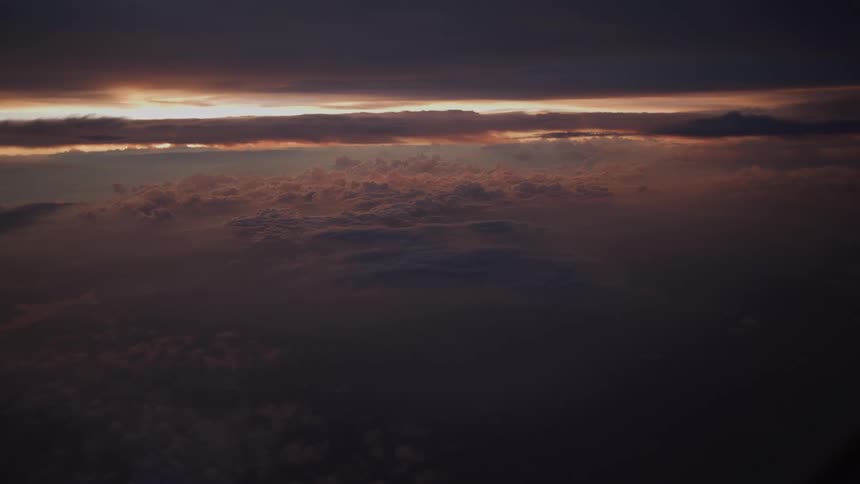 An atmospheric aerial view shows a beautiful but moody sunset breaking through dense layers of clouds