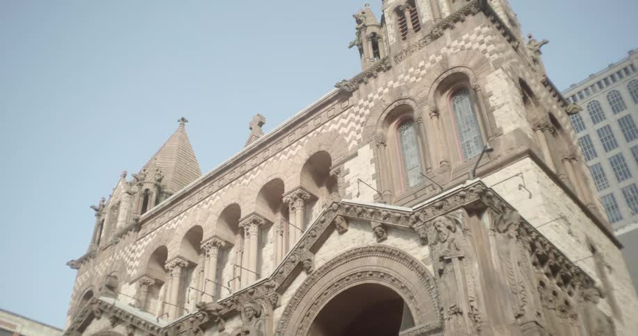 A low-angle shot slowly pans up the grand, detailed facade of a historic stone church on a clear day