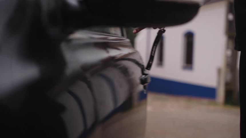 Close-up slow-motion shot of a hand using a key to unlock a shiny black car door