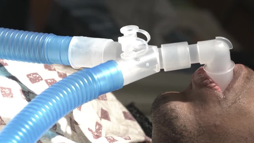 A close-up view of a patient breathing through a ventilator tube in a hospital setting