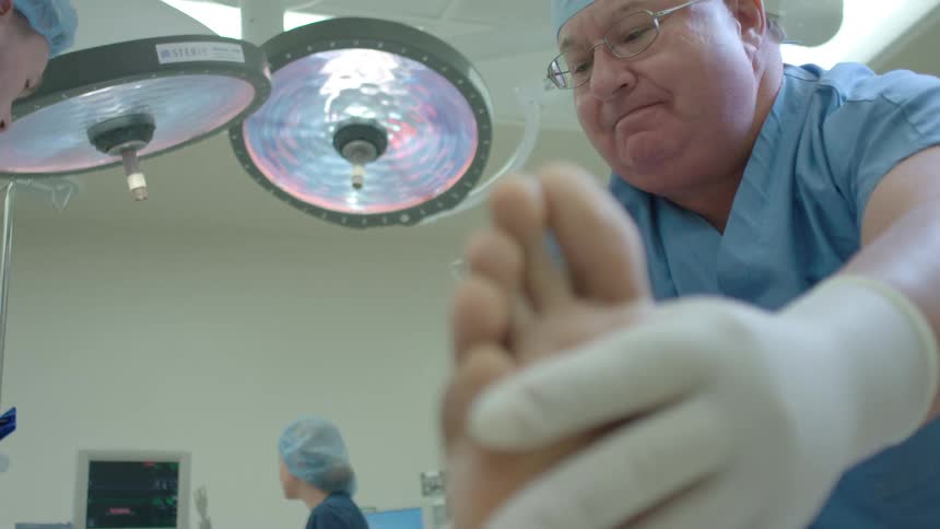 From a patient's point of view, a surgeon in scrubs examines a foot in a modern operating room