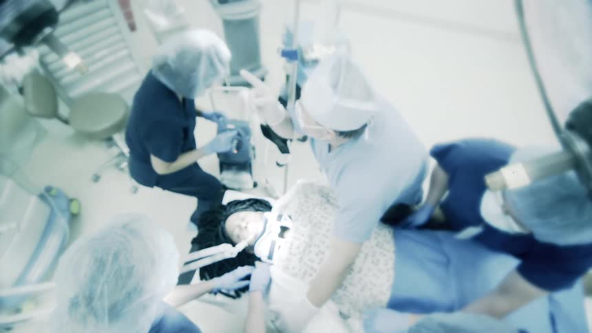 High-angle, soft-focus view of a dental team performing a procedure on a patient in a sterile clinic