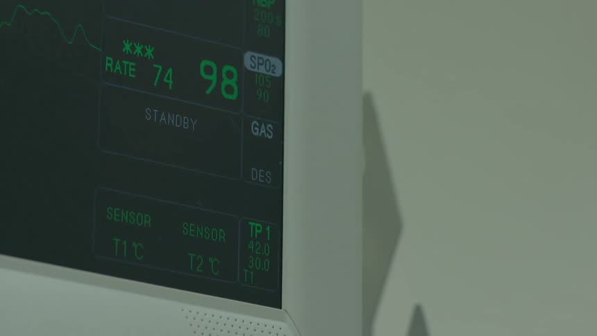 A close-up view of a hospital heart rate monitor displaying a patient's vital signs, including a steady waveform and numerical data
